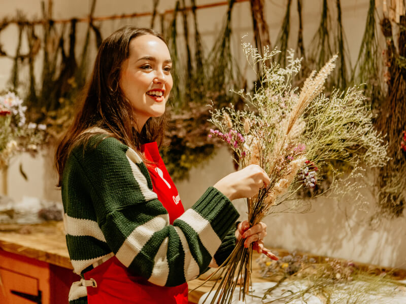 Smiling woman arranging a bouquet of dried flowers